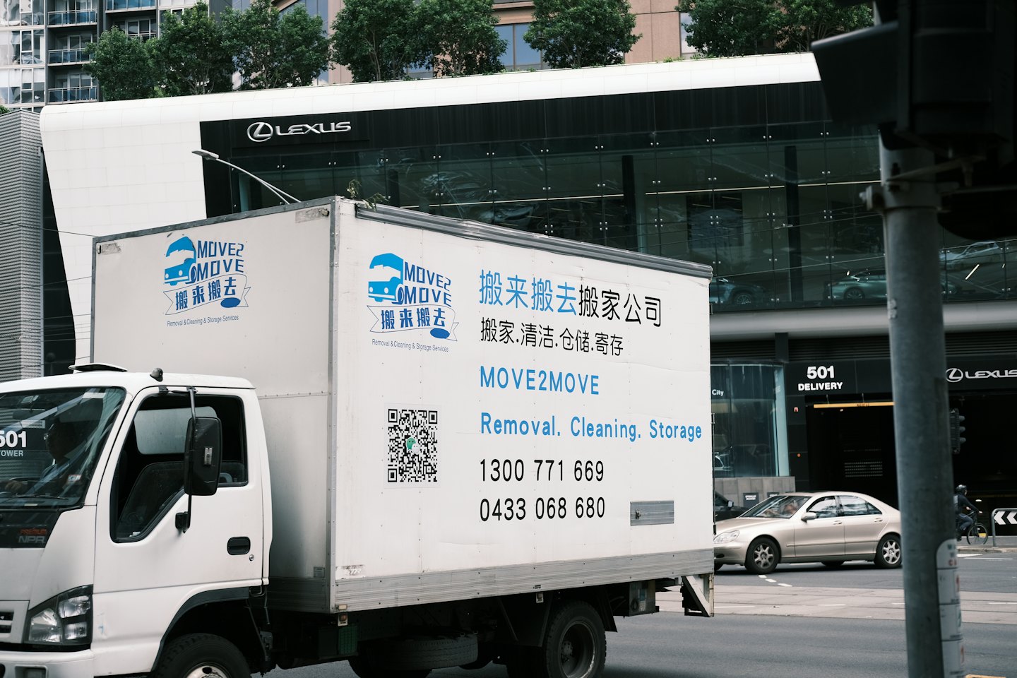 Moving truck with multilingual services driving on a city street.