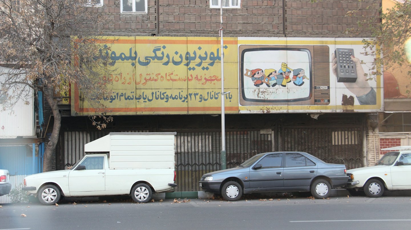 Yellow billboard advertising vintage televisions on a brick building.