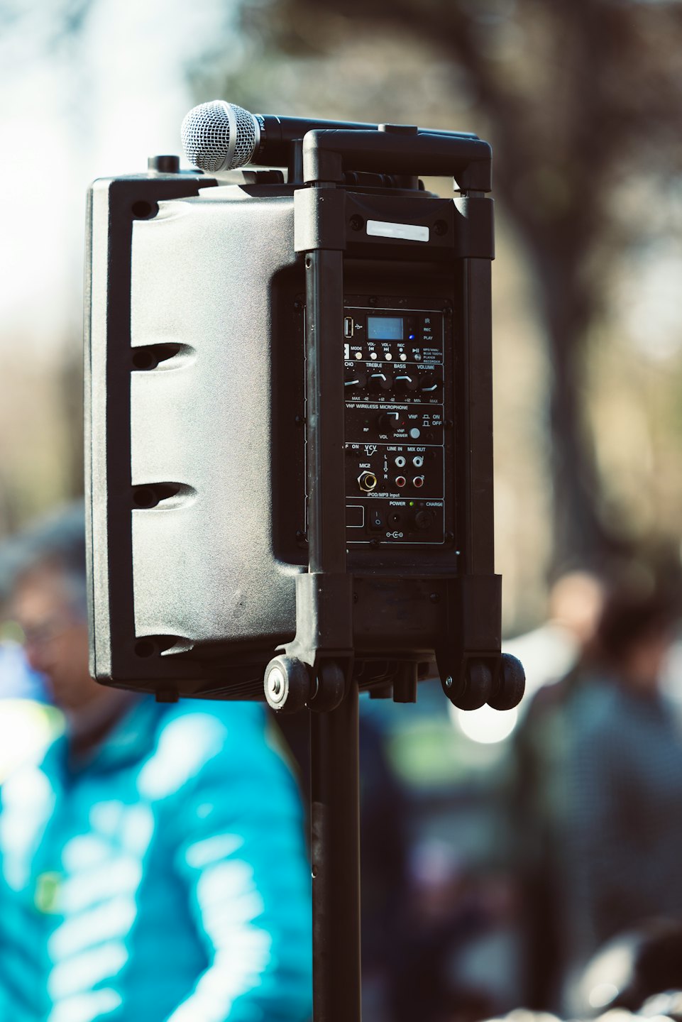 Grey PA speaker with microphone set up at outdoor event.