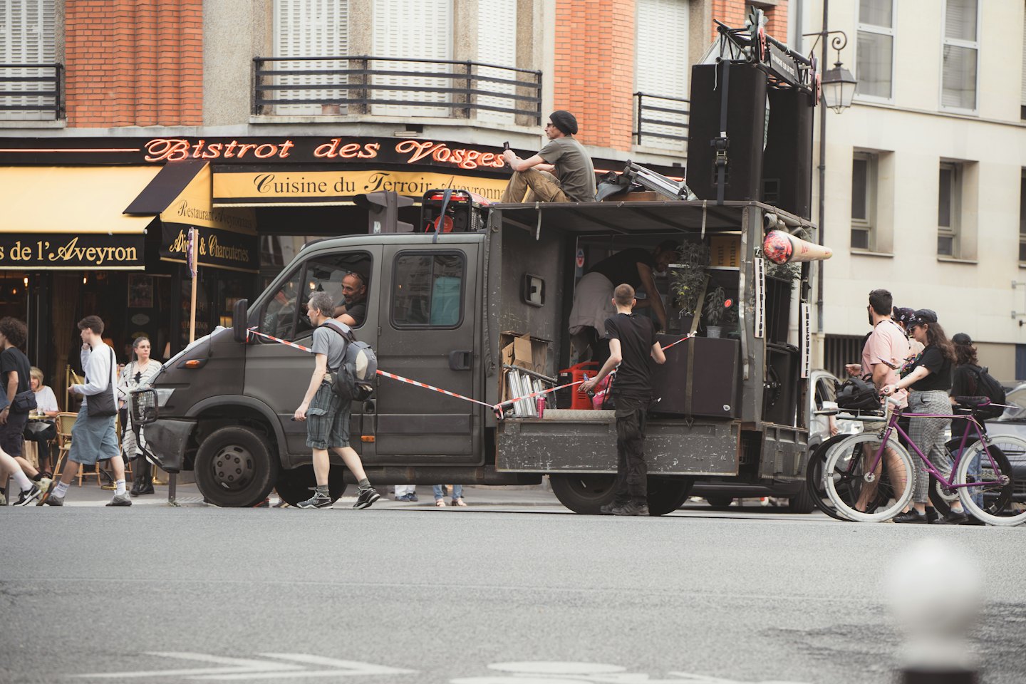 People gather around a mobile stage truck parked on the street.